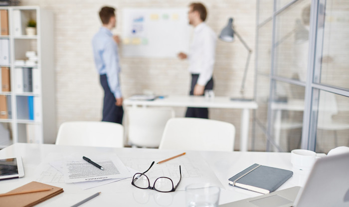 Empty workplace in office with businessmen interacting on background