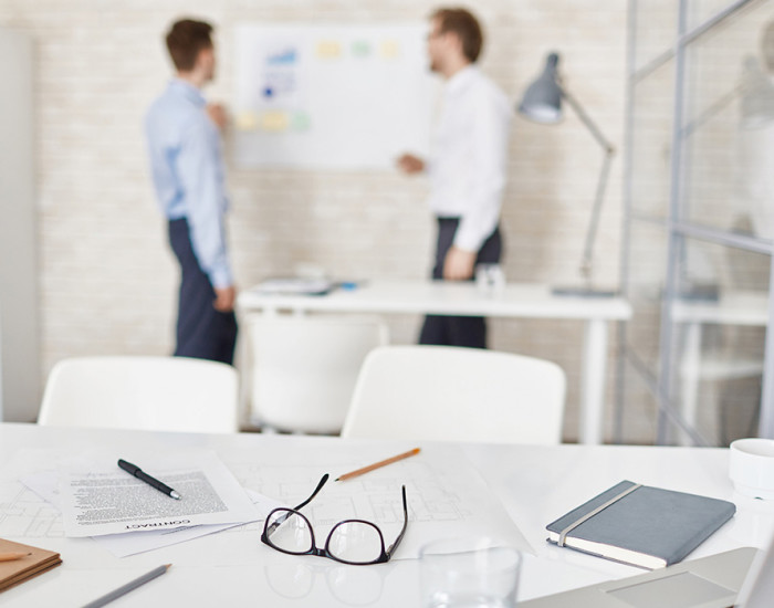 Empty workplace in office with businessmen interacting on background